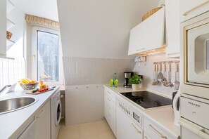 Cocina compacta con lavadora, estufa y lavabo.