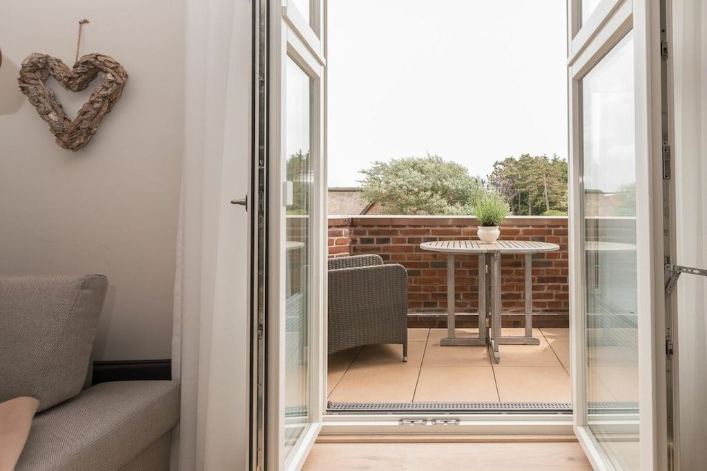 Een kamer met een glazen schuifdeur die uitkomt op een terras met een tafel en stoelen.