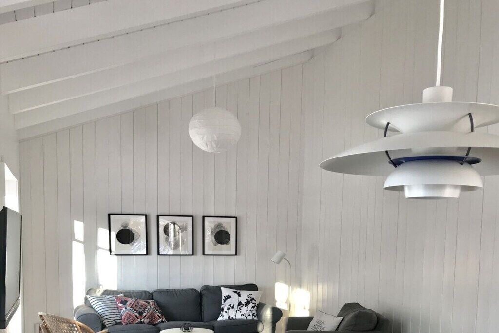 Una sala de estar moderna con un sofá, un colgador de luces y cuadros en la pared.