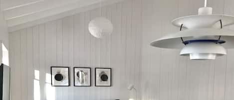 Una sala de estar moderna con un sofá, un colgador de luces y cuadros en la pared.
