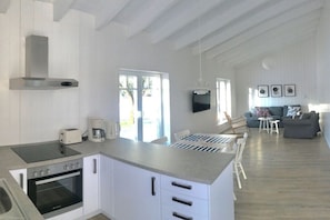 A modern kitchen with a built-in oven, a coffee maker, and a dining area with a table and chairs. - Holiday wooden house (Neustadt)