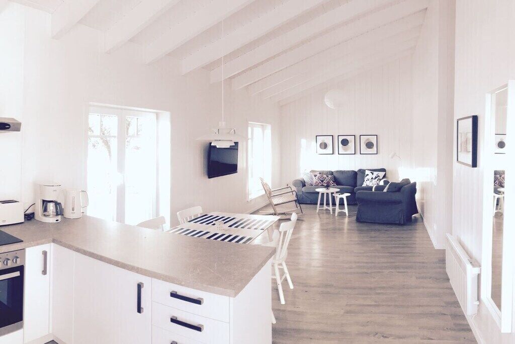 A modern kitchen with a central island, a dining area with a table and chairs, and a living room with a sofa and a coffee table.