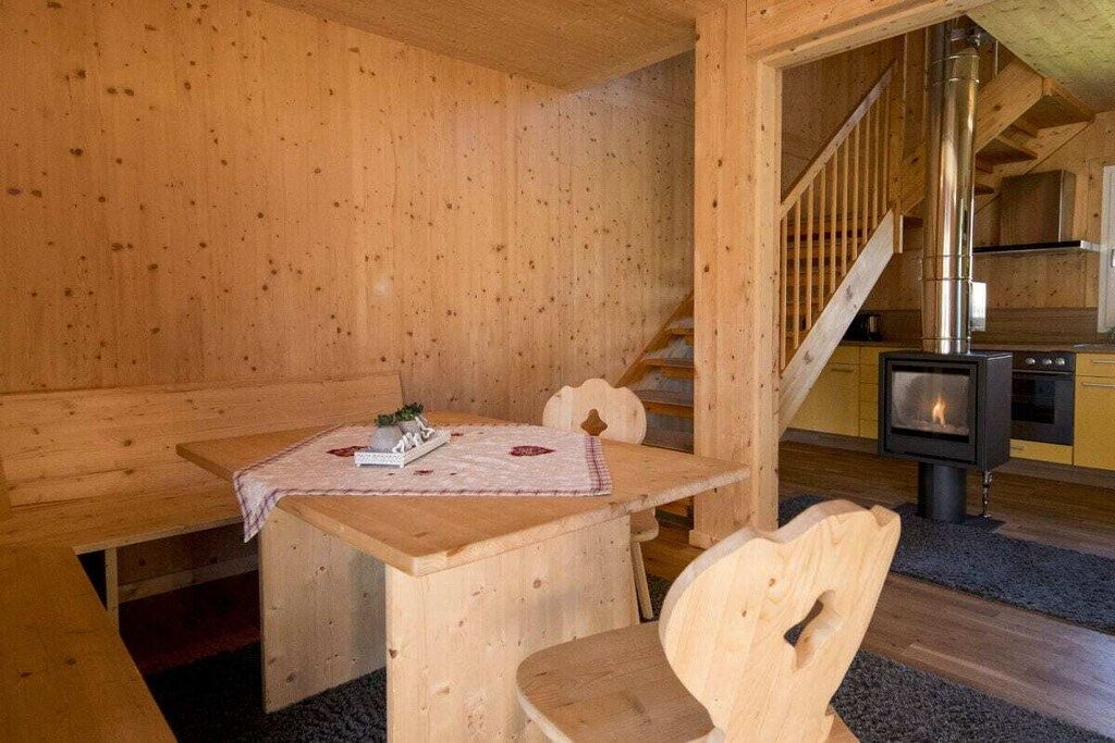 A wooden interior with a bench, table, and a fireplace.