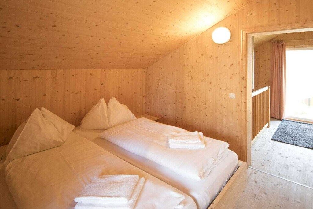 A wooden room with two beds, each with pillows and folded towels.