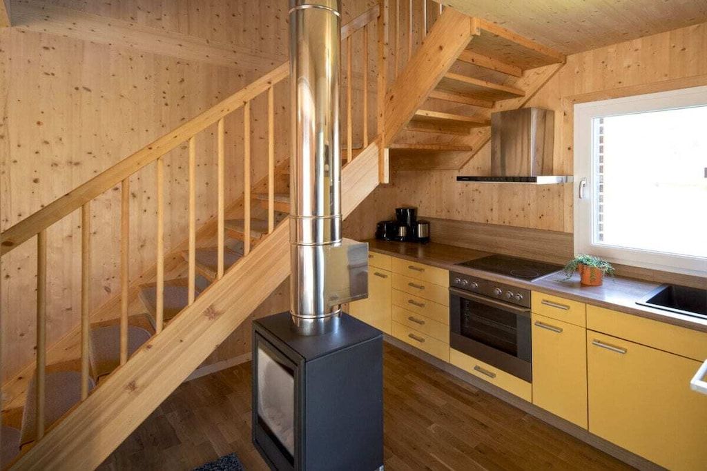 A wooden interior with a kitchen, a stove, and a staircase.