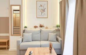 A modern living room with a light grey sofa, a wooden coffee table, and a framed abstract painting on the wall. - Jose Lasso de la Vega Romero (Málaga)