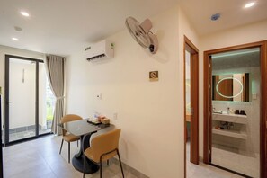 A hotel room with a dining area, a bathroom with a mirror and toiletries, and a sliding glass door to the outside. - Weal Hotel & Apartment (Da Nang)