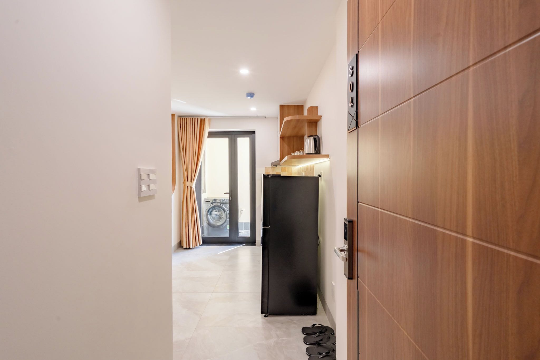 Un pasillo con un armario de madera, un refrigerador negro y una puerta que da a un área de lavandería.