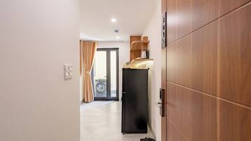 Un pasillo con un armario de madera, un refrigerador negro y una puerta que da a un área de lavandería.