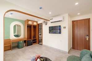 A modern living room with a wooden wardrobe, a TV mounted on the wall, and a small fridge. - Weal Hotel & Apartment (Da Nang)