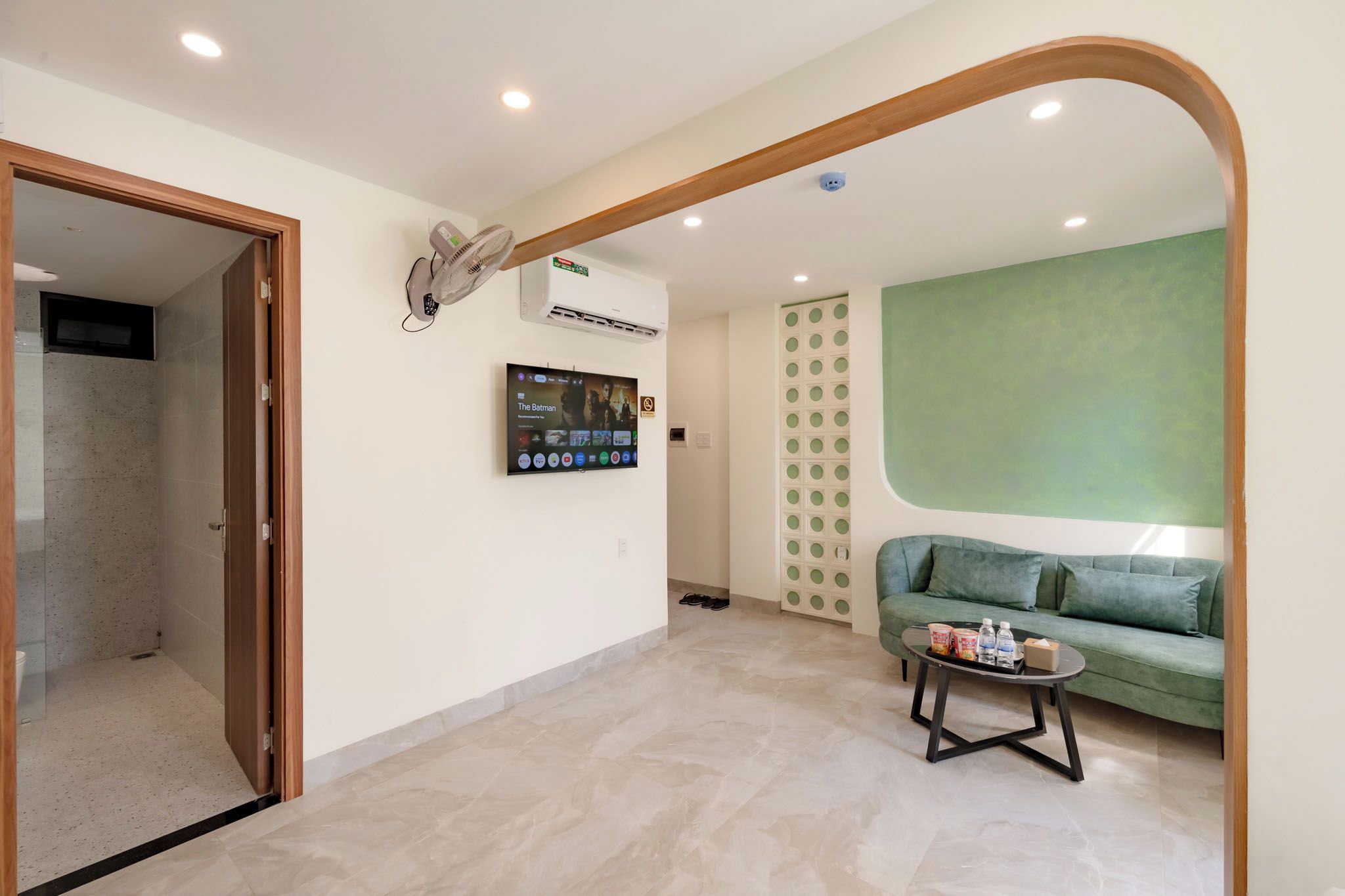 Una sala de estar moderna con un sofá verde, una mesa de centro y un televisor de pantalla plana montado en la pared.