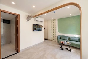 A modern living room with a green sofa, a coffee table, and a flat-screen TV mounted on the wall. - Weal Hotel & Apartment (Da Nang)