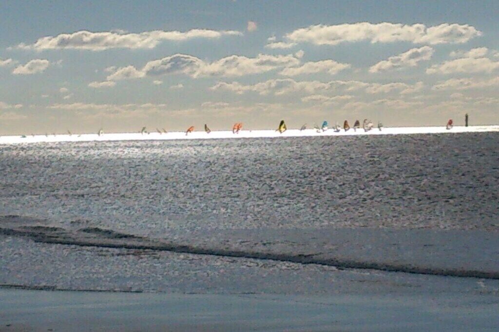 Une plage où l’on peut voir des gens pratiquer diverses activités, un ciel dégagé et une mer calme.