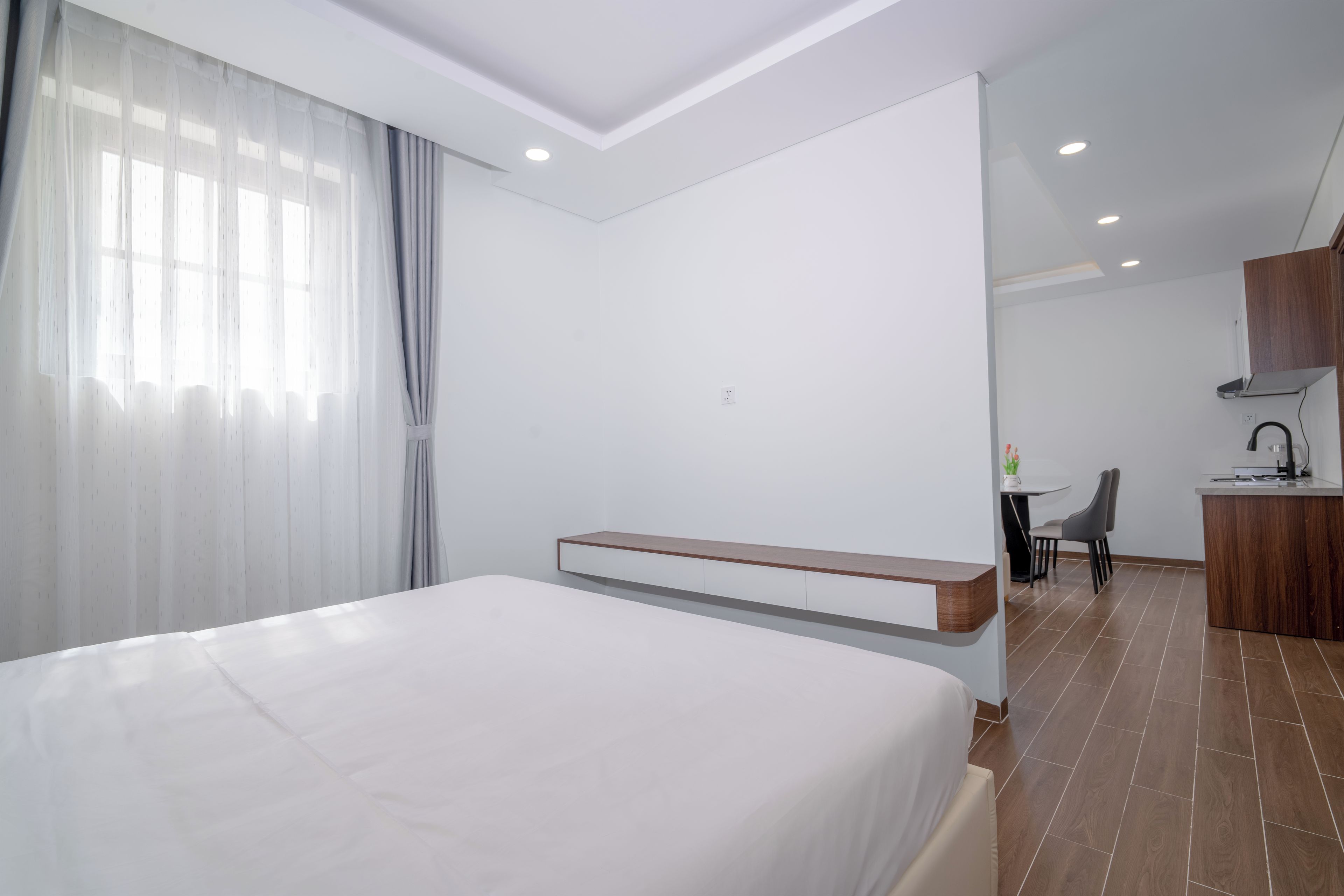 A hotel room with a bed, a desk, and a kitchenette.