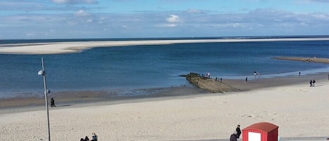 A beach with a red carriage, people walking, and a clear sky.