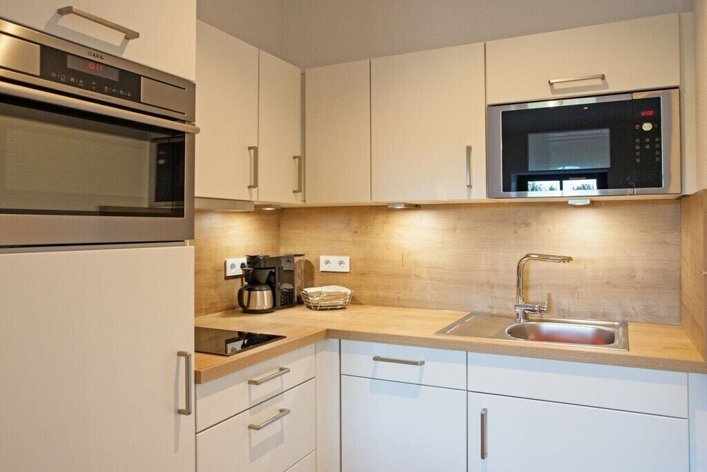 A compact kitchen with a built-in microwave, oven, and a coffee maker on the countertop.