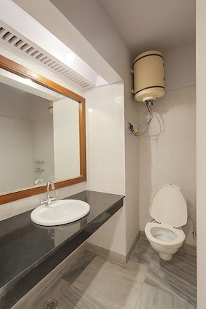 Un baño con lavamanos, espejo, inodoro y una lámpara en el techo.
