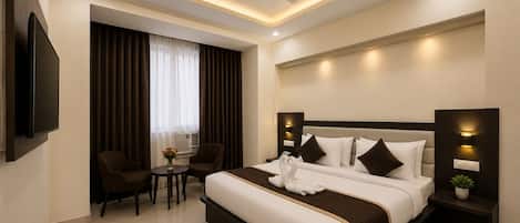 A modern hotel room with a large bed, a flat-screen TV, a ceiling fan, and a small table with a vase of flowers.