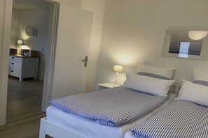 A hotel room with a bed, bedside tables, a lamp, and a door leading to another room. - Holiday home in Klein Waabs with Wi-Fi (Klein Waabs)