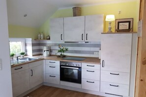 A kitchen with white cabinets, a stove, and a sink. - Country House Moor and Sea *2* (Ostgroßefehn)