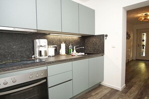 A modern kitchen with grey cabinets, a coffee maker, and a sink. - Holiday apartment with 1 bedroom (Sellin)