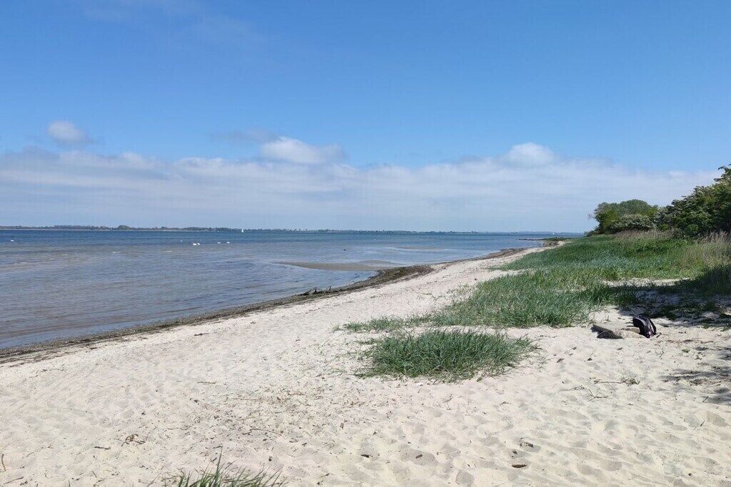 A sandy beach with a clear sky and calm water.