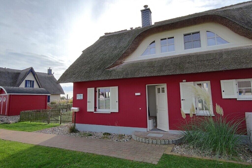 Ein rotes Gebäude mit einem Strohdach, einer weißen Tür und einer kleinen Veranda.
