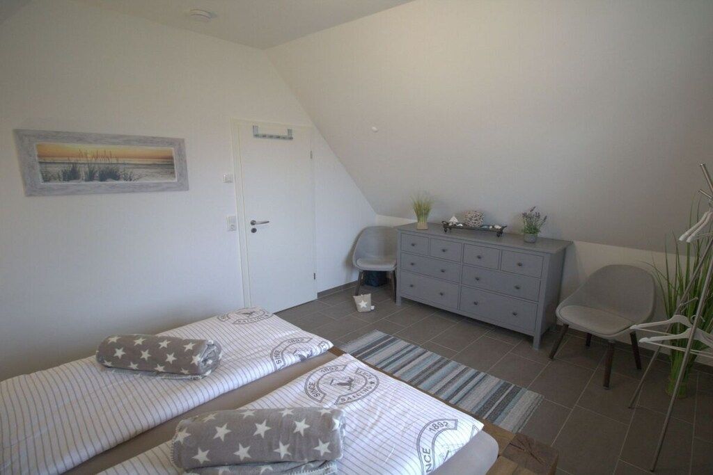 A bedroom with two beds, a dresser, a chair, and a painting on the wall.