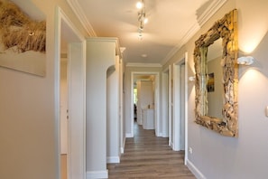 A hallway with white walls, wooden flooring, and a large mirror with a natural frame. - Westwind Country House (Keitum)