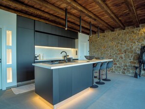Een moderne keuken met een centraal eiland, barkrukken en een stenen muur.