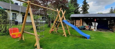 Un parque infantil con columpios, un tobogán y una silla roja y amarilla.