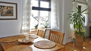 A dining area with a wooden table, woven placemats, and a potted plant. - Holiday apartment with 2 bedrooms (Kappeln Stadt)