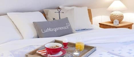 Una cama bien hecha con una bandeja de desayuno, una almohada con diseño de corazón y una lámpara de noche.