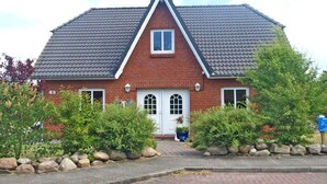 A two-story house with a red brick facade, a gabled roof, and a front entrance with a white door. - Holiday apartment with 2 bedrooms (Kappeln Stadt)
