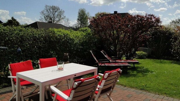 An outdoor patio with a table and chairs, a grill, and a tree with red leaves. - Holiday apartment with 2 bedrooms (Kappeln Stadt)