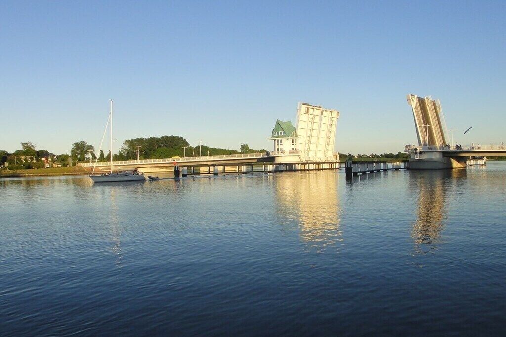 Un río con un puente, una barca y un edificio de techo verde.