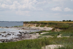 Eine Küstenlandschaft mit Sandstrand, felsigem Ufer und grasbewachsenen Dünen.