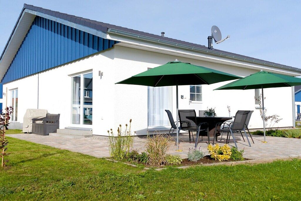 A modern house with a patio, outdoor furniture, and a satellite dish.