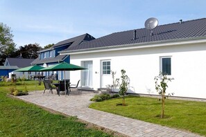 A residential building with a paved patio, outdoor furniture, and a small garden. - Holiday home in Altefähr with swimming pool (Altefähr)