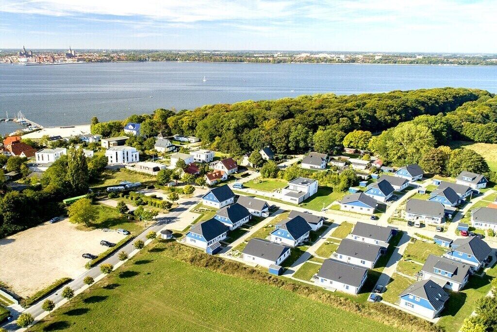 A residential area with houses arranged in a grid pattern, a body of water in the background, and a distant city skyline.