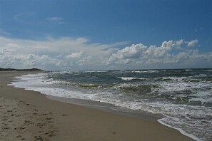 A beach with waves, a clear sky, and a distant shoreline. - Holiday apartment with 2 bedrooms (Norderney)