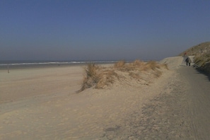A sandy beach with dunes and a clear sky. - Captain's House Schubert (Norderney)