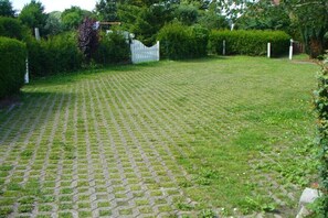 Una zona pavimentada amb una tanca blanca i vegetació.