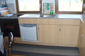 A compact kitchen with a dishwasher, a sink, and a window. - Holiday apartment with 2 bedrooms (Wangerland)