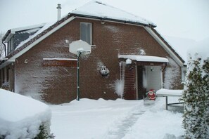 A brick building with a snow-covered roof and a basketball hoop in front. - Holiday apartment with 2 bedrooms (Wangerland)
