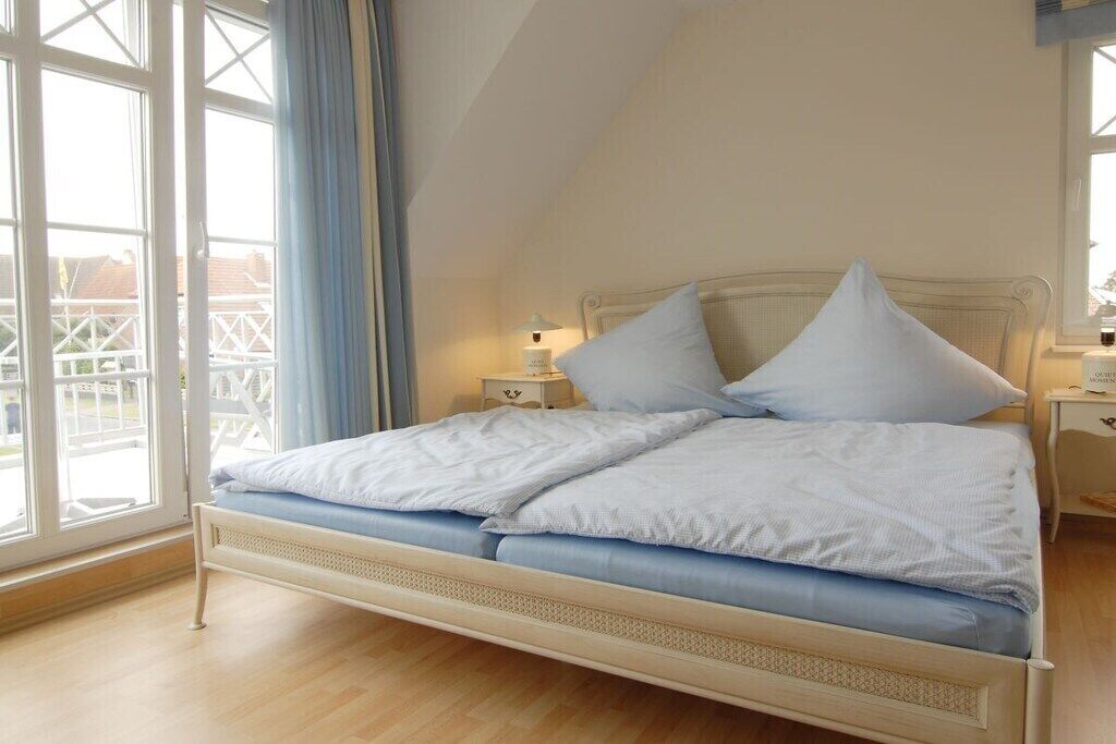 A bedroom with a bed, a nightstand, and a window with curtains.