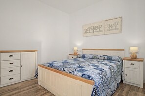 A bedroom with a bed, two nightstands, a dresser, and a wall-mounted artwork. - Holiday Home 'La Casa De Los Abuelos' with Private Pool in Conil (Conil de la Frontera)