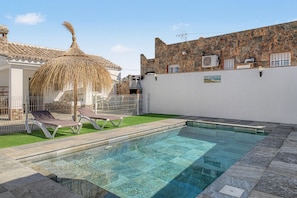 A swimming pool with clear water, surrounded by a stone deck and a grassy area with lounge chairs. - Holiday Home 'La Casa De Los Abuelos' with Private Pool in Conil (Conil de la Frontera)