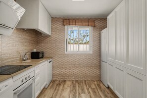 A compact kitchen with a stone backsplash, a window with a view, and white cabinetry. - Holiday Home 'La Casa De Los Abuelos' with Private Pool in Conil (Conil de la Frontera)