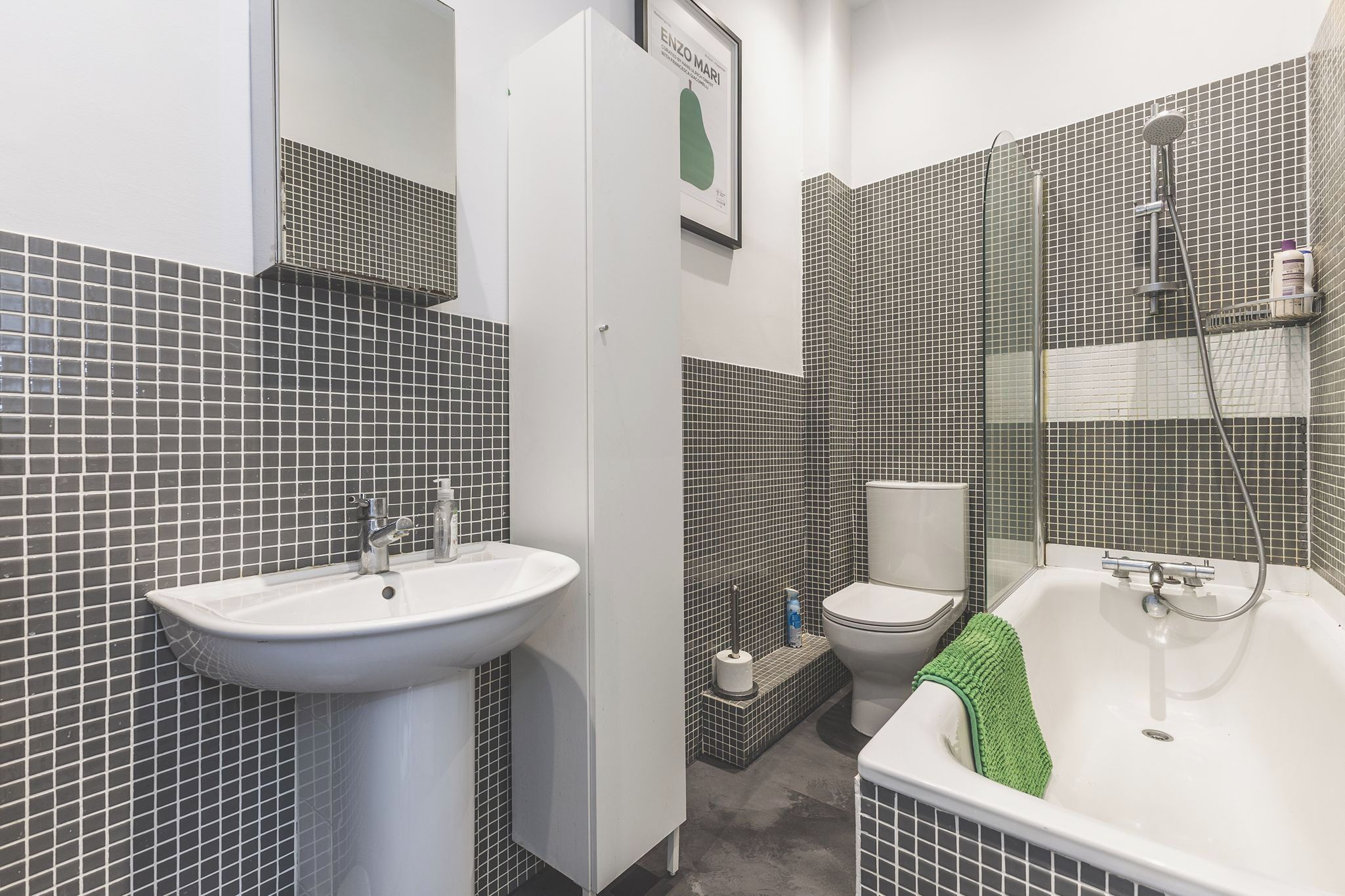 Une salle de bain comprenant un lavabo, des toilettes et une baignoire, le tout avec des murs carrelés.